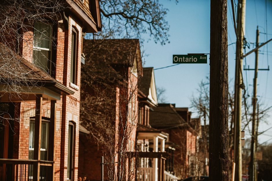 Ontario multiplex housing street view with for-sale signs highlighting missing-middle affordability opportunity.